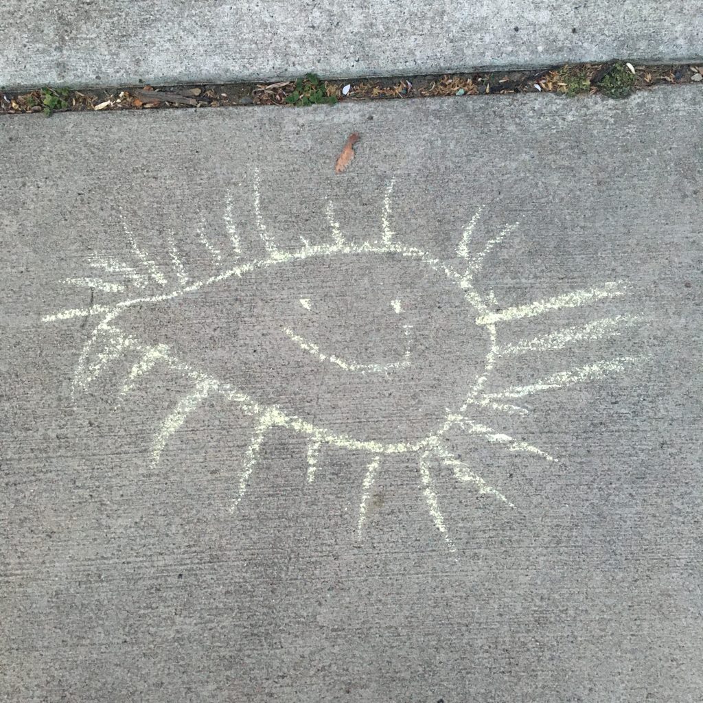 Yellow chalk water drop-shaped entity with lots of rays and a smile. 
